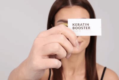 Modèle appliquant l'étape 3 - Keratin Booster sur les cils